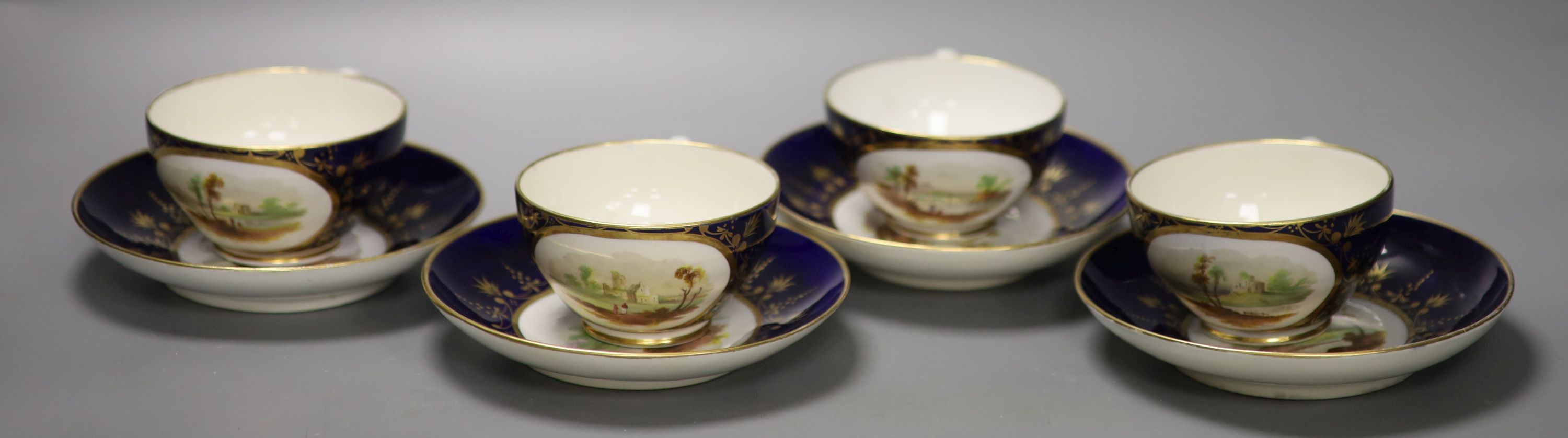 A set of four Derby cups and saucers painted with landscapes on a cobalt blue ground by Henry Lark Pratt, red mark